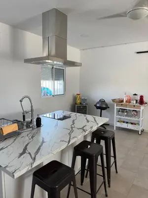 a kitchen with a large marble counter and stools at Casa con piscina Sanlúcar de Barrameda in Sanlúcar de Barrameda
