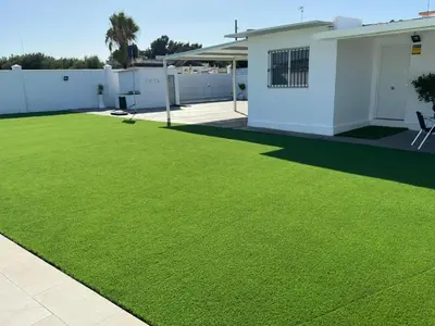 a yard with green grass in front of a house at Casa con piscina Sanlúcar de Barrameda in Sanlúcar de Barrameda