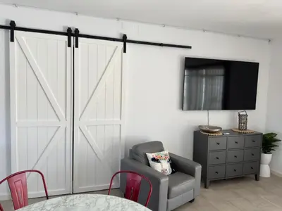 a sliding barn door in a living room with a chair at Casa con piscina Sanlúcar de Barrameda in Sanlúcar de Barrameda