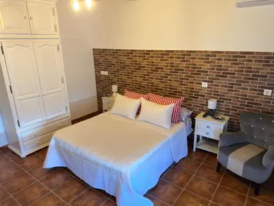 a bedroom with a bed and a chair at Casa con piscina Sanlúcar de Barrameda in Sanlúcar de Barrameda
