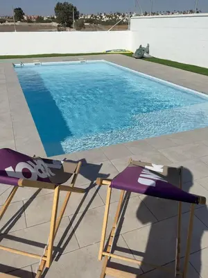 a pair of chairs sitting next to a swimming pool at Casa con piscina Sanlúcar de Barrameda in Sanlúcar de Barrameda