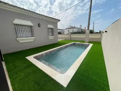 a backyard with a swimming pool and green grass at Villa Bolet in Chiclana de la Frontera