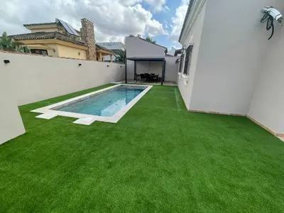 a backyard with green grass and a swimming pool at Villa Bolet in Chiclana de la Frontera