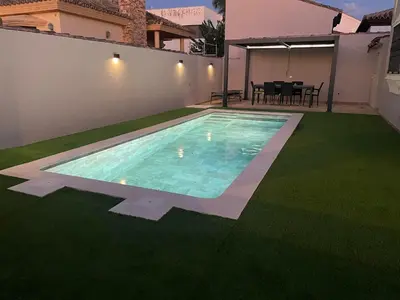 a backyard with a swimming pool and green grass at Villa Bolet in Chiclana de la Frontera