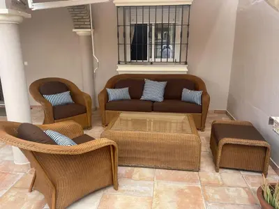 a living room with a couch and wicker chairs at Villa Bolet in Chiclana de la Frontera