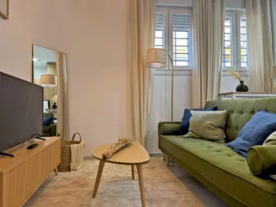a living room with a green couch and a television at Apartamento Clavel - Ole Solutions in Jerez de la Frontera