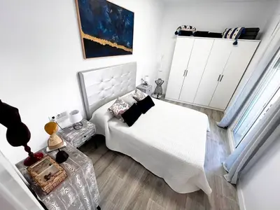 a white bedroom with a bed and a table at Casa Moderna con Garaje en Rota, cerca de Playa in Rota