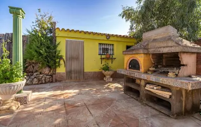a patio with a yellow house with an outdoor oven at Stunning Home In Chiclana De La Fronter in Novo Sancti Petri