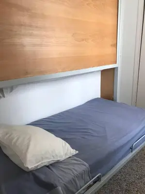 a bed with a wooden headboard and a pillow at Apartamento primera linea de playa in Rota