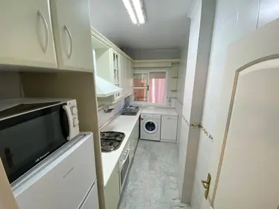 a white kitchen with a stove and a microwave at Apartamento Calzada Centro, Calle Hermano Fermín in Sanlúcar de Barrameda