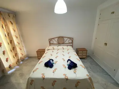 a bedroom with a bed with a floral bedspread at Apartamento Calzada Centro, Calle Hermano Fermín in Sanlúcar de Barrameda