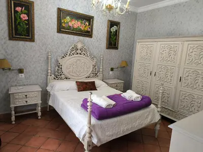 a bedroom with a white bed with purple sheets at Cielos Casona in El Puerto de Santa María
