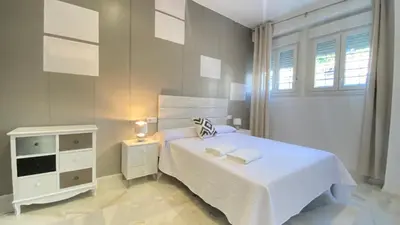 a white bedroom with a white bed and a window at People Homes Clavel in Jerez de la Frontera