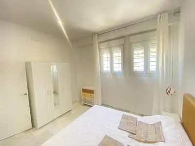 a white bedroom with a bed and a window at People Homes Clavel in Jerez de la Frontera