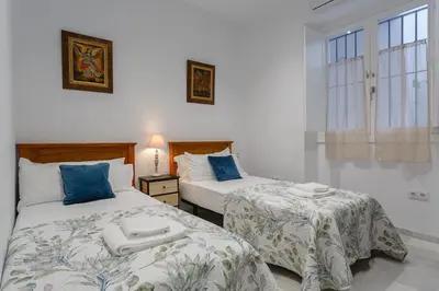 a bedroom with two beds with blue and white sheets at Apartamento Miracadiz in Cádiz