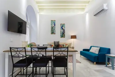 a living room with a dining table and a blue couch at Apartamento Miracadiz in Cádiz