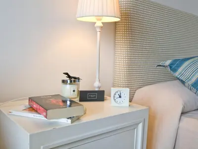 a bedside table with a lamp and books and a clock at Villa 210 by Villamya in Arcos de la Frontera