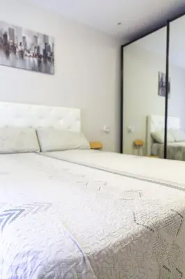 a white bed in a room with a mirror at El Caletero by Gades Gestión in Cádiz
