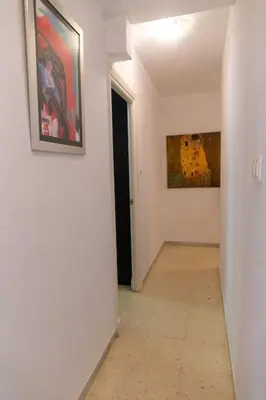 a hallway with two paintings on the wall and a door at El Caletero by Gades Gestión in Cádiz