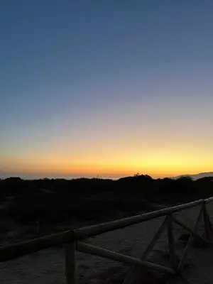 a sunset over the ocean with a wooden fence at Casita de la playa en Durango in El Puerto de Santa María