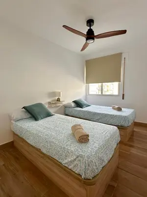 two beds in a room with a ceiling fan at Casita de la playa en Durango in El Puerto de Santa María