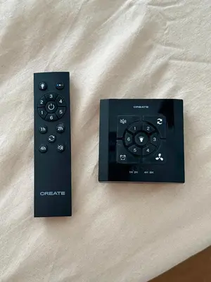 two black remote controls sitting on a bed at Casita de la playa en Durango in El Puerto de Santa María
