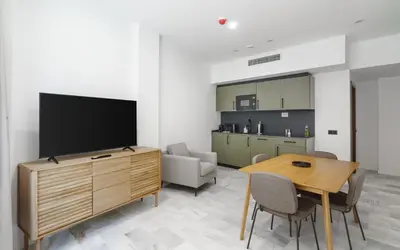 a living room with a tv and a table with chairs at Limehome Jerez de la Frontera Marqués de Casa-Domecq in Jerez de la Frontera