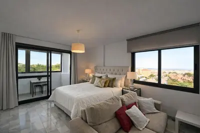 a bedroom with a bed and a couch and windows at Vistahermosa Piscina Vistas in El Puerto de Santa María