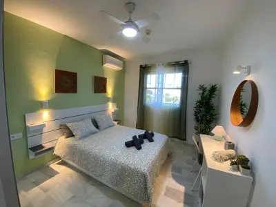 a bedroom with a bed and a mirror and a table at Apartamento Di Matteo, Playa-Piscina in Sanlúcar de Barrameda