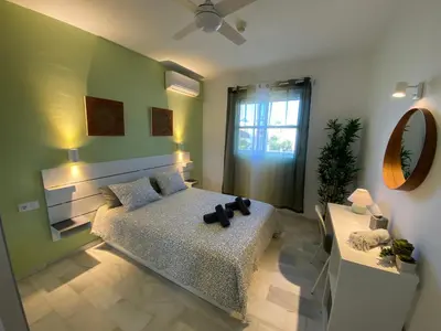 a bedroom with a bed and a mirror and a table at Apartamento Di Matteo, Playa-Piscina in Sanlúcar de Barrameda