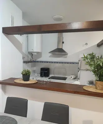 a kitchen with a sink and a counter with chairs at Apartamento Di Matteo, Playa-Piscina in Sanlúcar de Barrameda