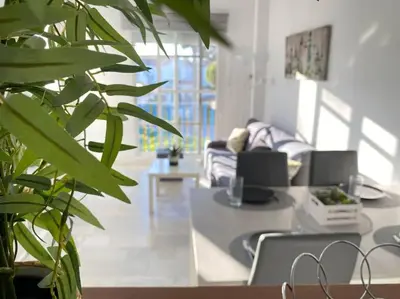 a living room with a table and a plant at Apartamento Di Matteo, Playa-Piscina in Sanlúcar de Barrameda