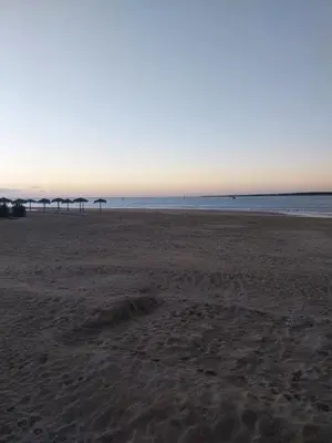 an empty beach with umbrellas in the distance at PLAYA PASEO MARITIMo in Sanlúcar de Barrameda
