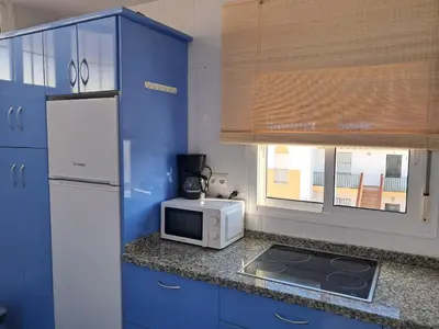 a kitchen with blue cabinets and a white microwave at PLAYA PASEO MARITIMo in Sanlúcar de Barrameda