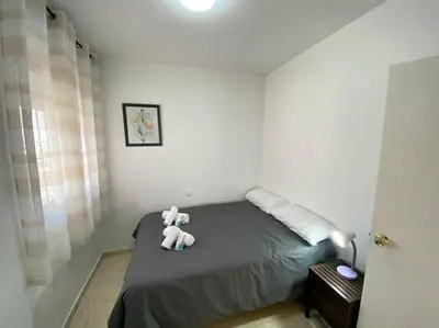 a teddy bear sitting on a bed in a bedroom at Apartamento Parque Bolsa in Sanlúcar de Barrameda