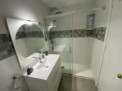 a white bathroom with a sink and a shower at Apartamento Parque Bolsa in Sanlúcar de Barrameda