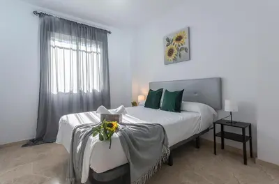 a white bedroom with a large bed with flowers on it at Amplio y Luminoso 3 Rooms Parking in Jerez de la Frontera