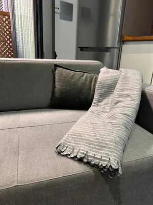 a gray couch with a throw pillow on it at Estudio Casa Palacio 2Pax wifi gratis in Sanlúcar de Barrameda