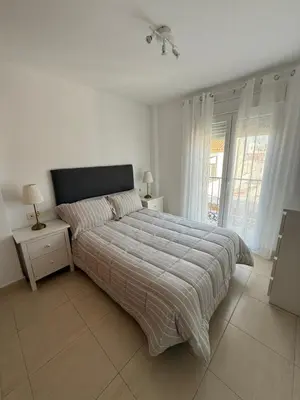 a white bedroom with a bed and a window at Piso completo en Chiclana de la Frontera in Chiclana de la Frontera
