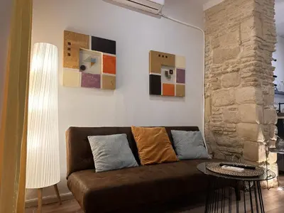 a living room with a brown couch and some paintings at Apartamento Santa Clara - Ole Solutions in Jerez de la Frontera