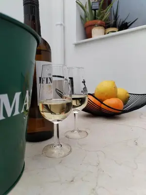 two glasses of white wine next to a basket of fruit at Patio & Sherry Apartamento in Jerez de la Frontera