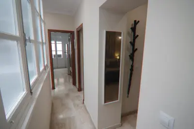 a hallway with white walls and a room with windows at Apartamento Ficus junto a la playa Cádiz in Cádiz