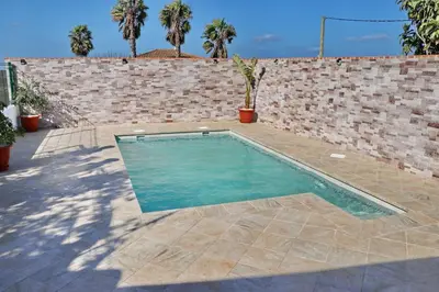 a swimming pool in front of a brick wall at Chalet Mendoza in Conil de la Frontera