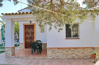 a front porch of a white house with a black chair at Chalet Mendoza in Conil de la Frontera