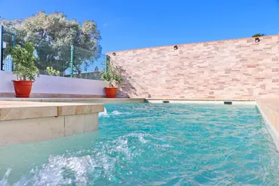 a pool of water with potted plants next to a brick wall at Chalet Mendoza in Conil de la Frontera