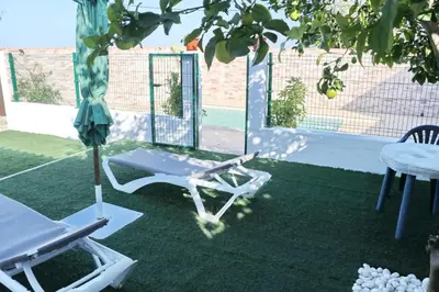 a patio with a table and a chair on the grass at Chalet Mendoza in Conil de la Frontera
