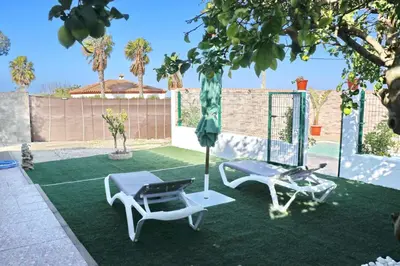 a patio with two chairs and a table and an umbrella at Chalet Mendoza in Conil de la Frontera