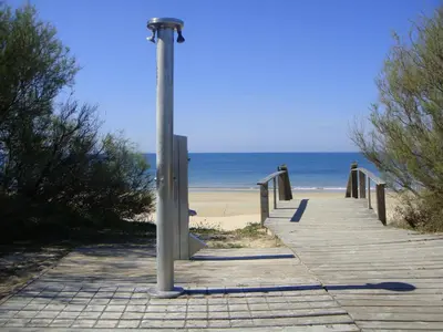 a wooden boardwalk leading to the beach with a pole at Life Apartments Costa Ballena in Costa Ballena
