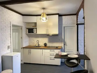 a kitchen with white cabinets and a table and a sink at Apartamento Plaza del Cabildo - Sanlúcar Centro in Sanlúcar de Barrameda