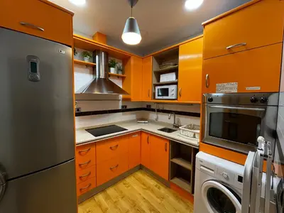 a kitchen with orange cabinets and a stainless steel refrigerator at El patio de la Pepa Grupo Ac Gestion in Cádiz